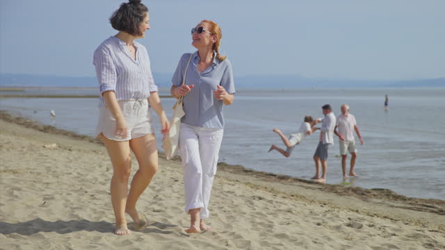 SLO MO TS Woman talking to her mother in law while walking on the beach