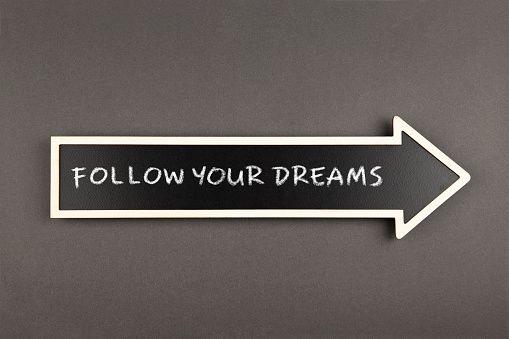 Arrow with text Follow your dreams, on blackboard