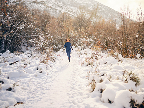 A young woman athlete on a snowy trail winter training run in Utah USA.