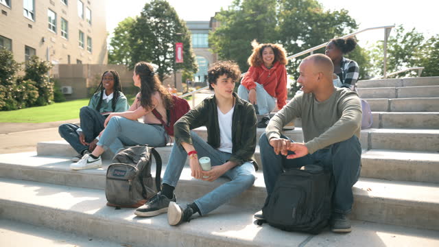 Group of university students sitting on the steps of a faculty building