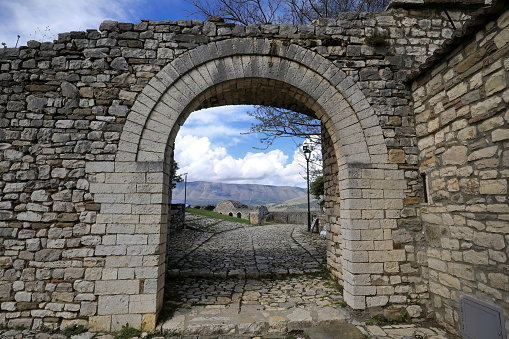 Westwards view across a stone masonry round arch over the fortress wall and the old garrison building ruins to the Shpirag Mal-Mount beyond the Osum river valley. Kala -Castle- district-Berat-Albania.