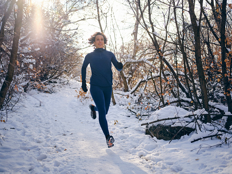 A young woman athlete on a snowy trail winter training run in Utah USA.