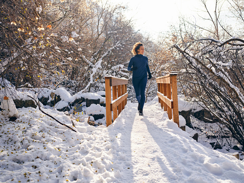 A young woman athlete on a snowy trail winter training run in Utah USA.