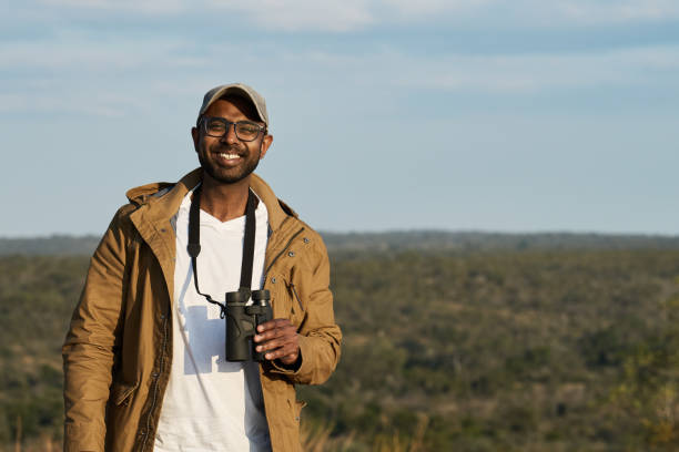 istock Smiling young man with binoculars standing on a hill in a nature reserve 1823310921