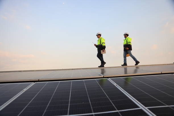 istock Two special Electrical engineers in safety suits worked and checked the solar system on the roof after installing,  walking on the roof against the blue sky and photovoltaic panel. 1823326731