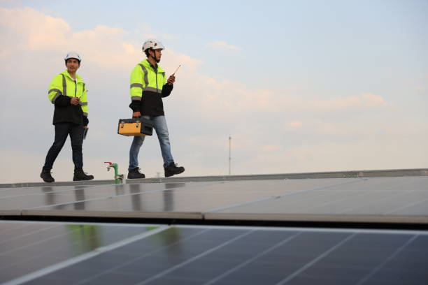 istock Two special Electrical engineers in safety suits worked and checked the solar system on the roof after installing,  walking on the roof against the blue sky and photovoltaic panel. 1823326736
