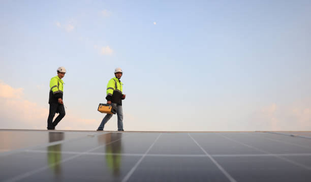 istock Two special Electrical engineers in safety suits worked and checked the solar system on the roof after installing,  walking on the roof against the blue sky and photovoltaic panel. 1823326737