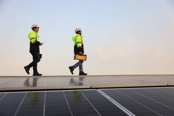 istock Two special Electrical engineers in safety suits worked and checked the solar system on the roof after installing,  walking on the roof against the blue sky and photovoltaic panel. 1823326738