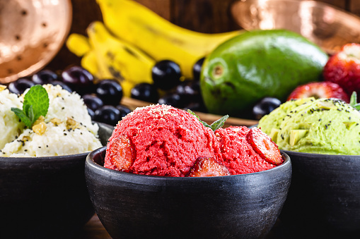 vegan ice cream made with organic fruits, with tropical fruits in the background, flavors of strawberry, banana, jabuticaba and avocado