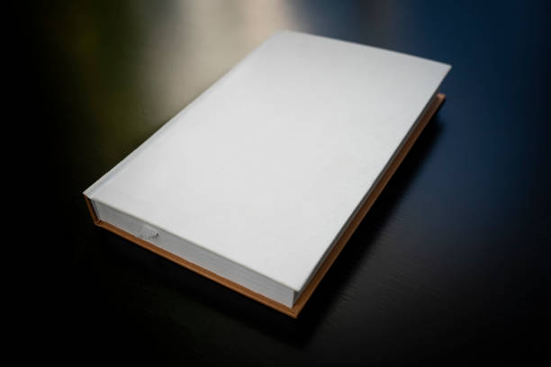 istock Closed white book with hard cover on black table, top view. Space for text 1823392481