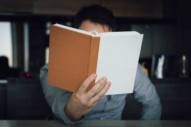 istock man reading book on couch. Bearded male thoughtfully studying literature 1823392489
