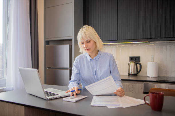 istock Young woman using calculator while going through bills and home finances 1823397452