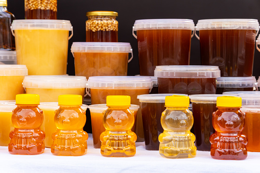 Many jars with fresh organic honey on farm market. Colorful honey with nuts in the jar, on a market in Altai.