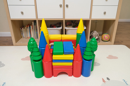 Construction of a children's building from designer cubes on the nursery floor. The castle is built from a multi-colored constructor
