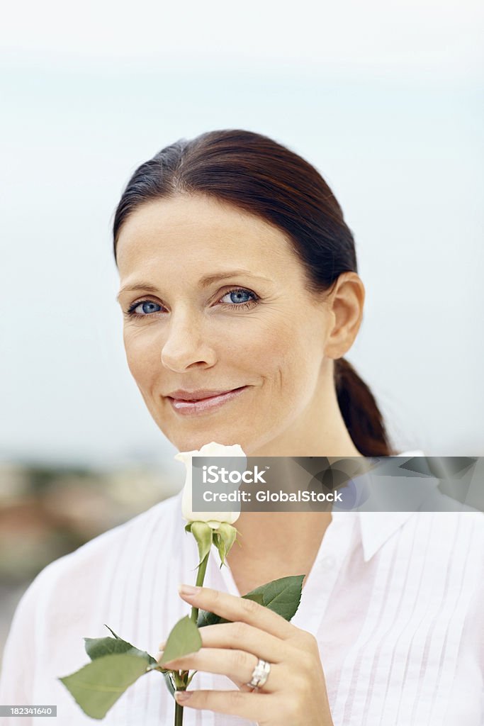Smiling mid adult lady holding a flower Portrait of a smiling mid adult lady holding a flower 30-39 Years Stock Photo