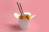 Box with Thai food. Noodles with chicken mushrooms and vegetable on bright pink background color.
