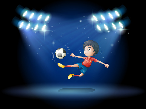 young boy playing soccer with spotlights