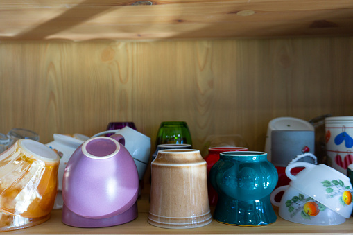 Cups in the kitchen cabinet. Colorful cups. Colorful cups used for tea and coffee. Kitchen cabinet layout.