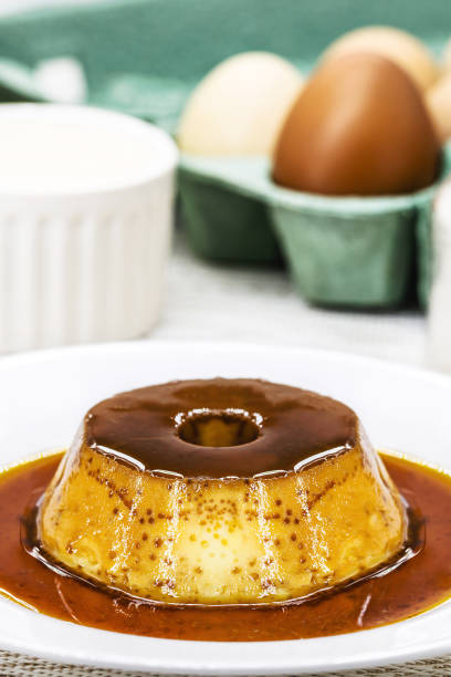 istock Small condensed milk pudding, with ingredients in the background, eggs, sugar, cinnamon, caramel and condensed milk, Homemade sweet recipe. 1823441038