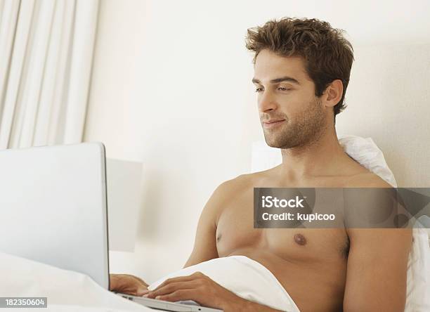 Hombre Atractivo Joven Usando Una Computadora Portátil En La Habitación Mientras Está En La Cama Foto de stock y más banco de imágenes de 20 a 29 años