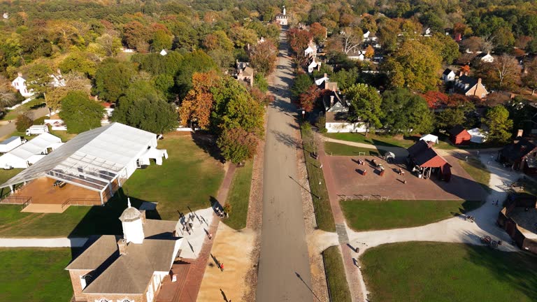 Autumnal E Duke of Gloucester in tree area of Colonial Williamsburg, Virginia. Aerial footage with forward toward the Capitol building. Remote, long flight camera motion