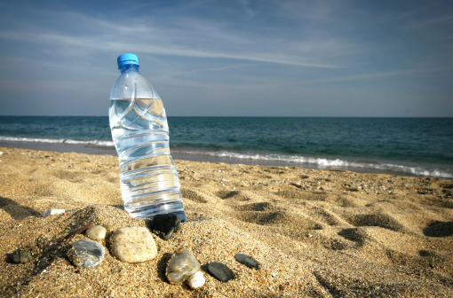 bottle of fresh cool water on a sand beach