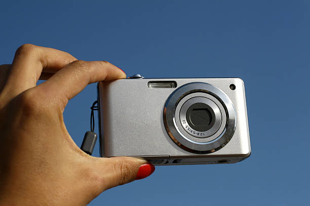 istock photocamera in hand over a blue sky 182353403