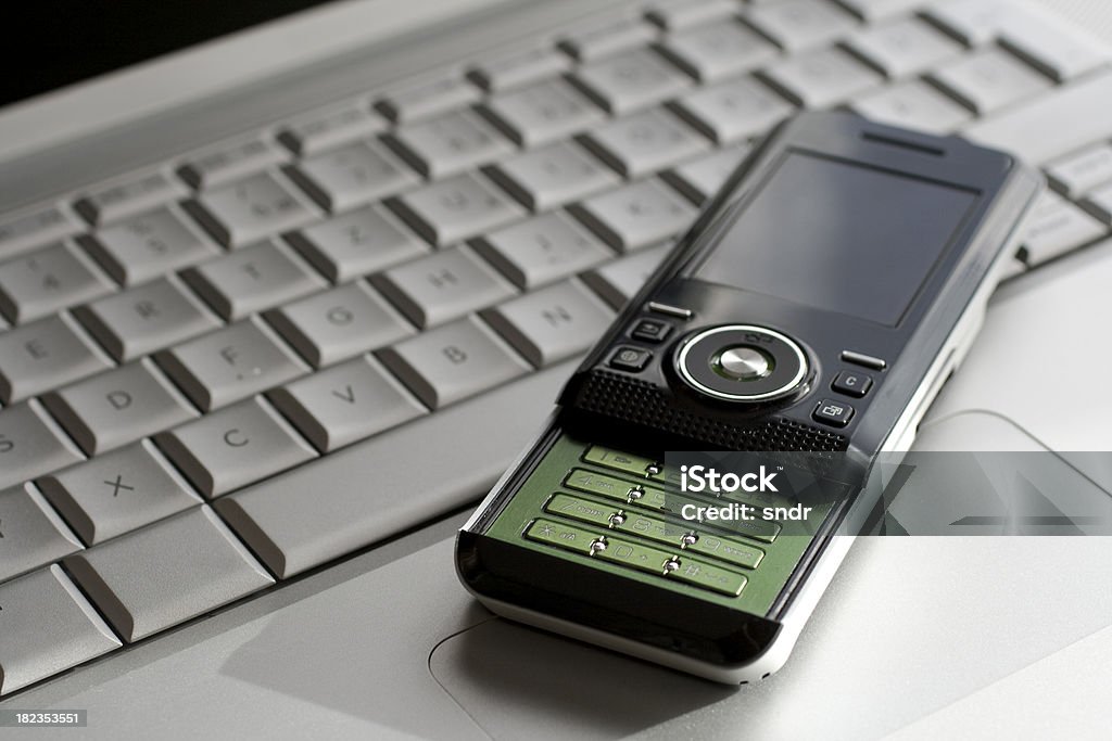 Telefone celular em um laptop - Foto de stock de Cinza - Descrição de Cor royalty-free