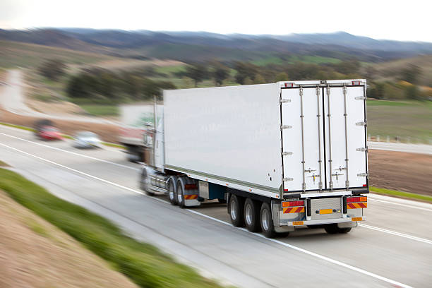 istock White semi trailer zooms down highway with motion blur 182354008