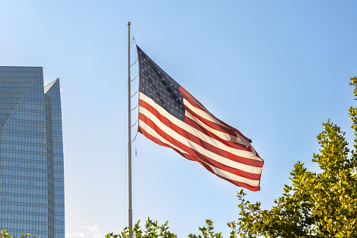 Oklahoma City, USA - October 25th, 2023: Devon Energy Center corporate skyscraper in downtown and flag of United states of America.