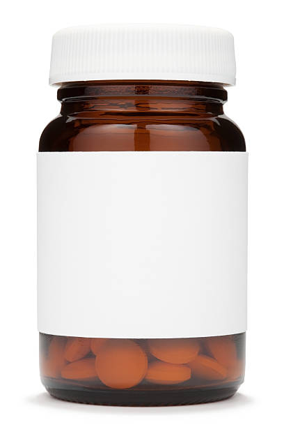 Closed brown glass jar with a blank label containing pills stock photo