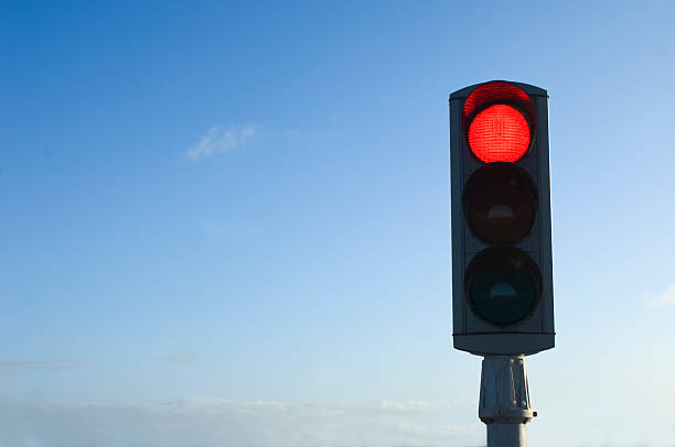 feu de signalisation sur rouge isolé contre ciel bleu - red light photos et images de collection