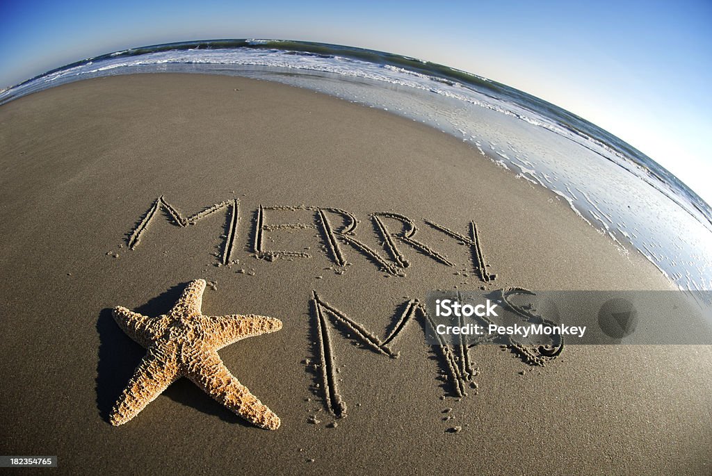 Merry Xmas Christmas Message with Starfish in Sand Starfish features in a Christmas message on deserted beach with fun fisheye perspective Beach Stock Photo