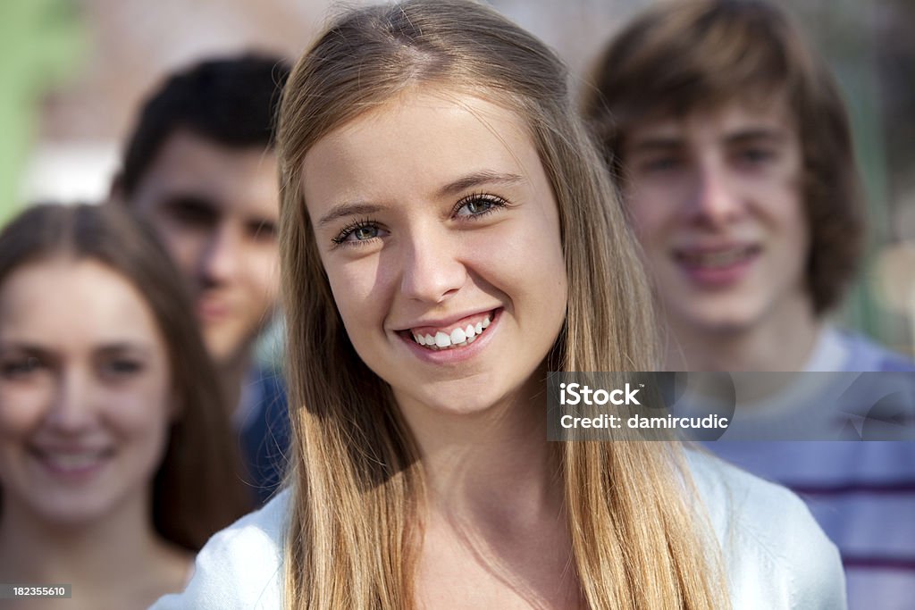 Bela Jovem mulher a sorrir e a pé com os seus amigos - Royalty-free Olhar para a Câmara Foto de stock