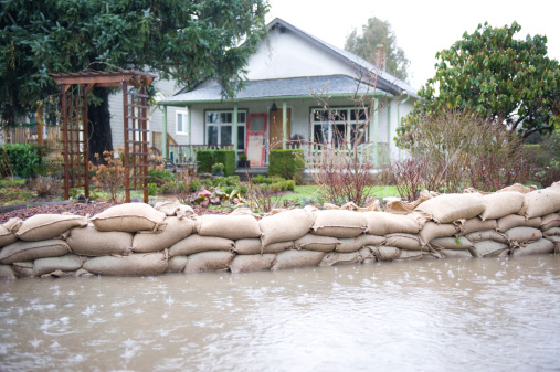 Home in background with sandbags and water surrounding it.