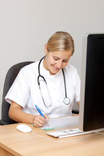 Young nurse writing on medical chart
