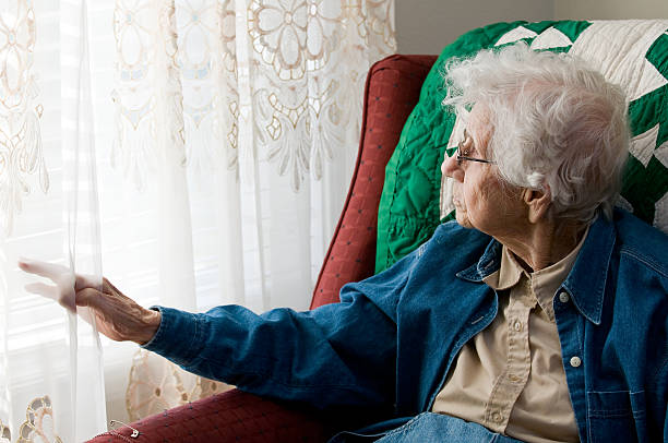 istock Elderly woman looking out window 182356743