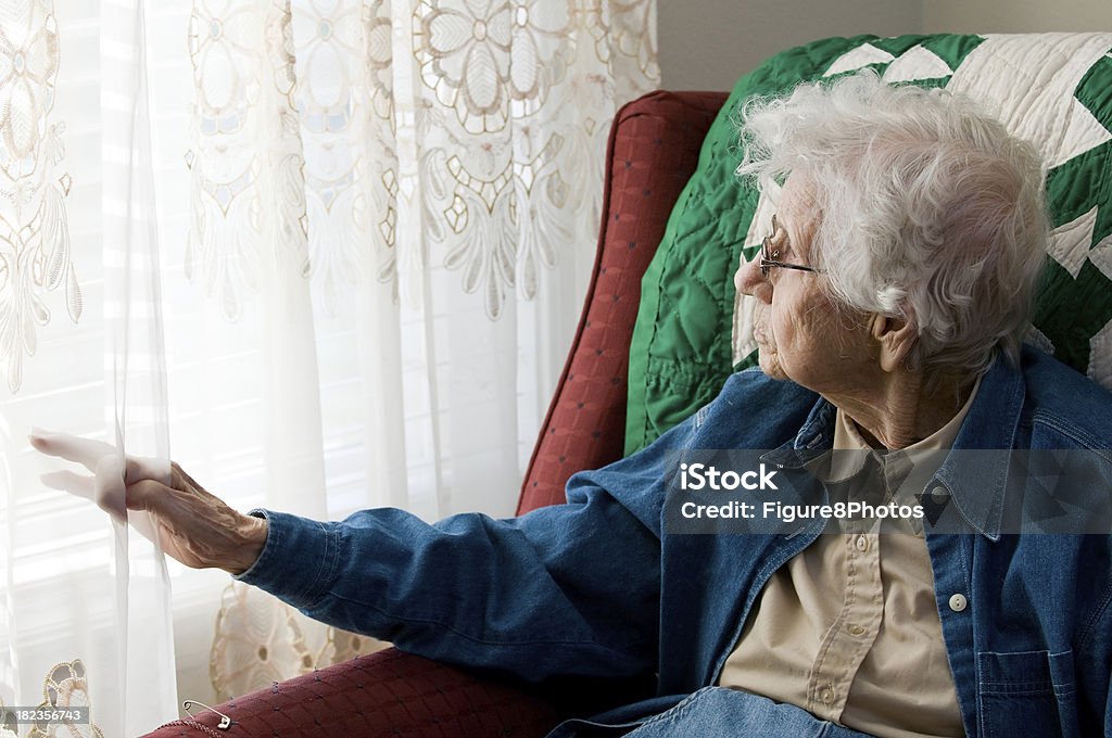 Elderly woman looking out window 96 year old great grandmother sitting in a chair. 80-89 Years Stock Photo