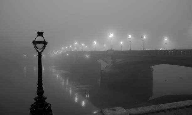 London In The Fog "A blanket of fog hangs over London, giving it a real Film Noir atmosphere. The lights of Battersea Bridge are reflected in the dark waters below." wandsworth photos stock pictures, royalty-free photos & images