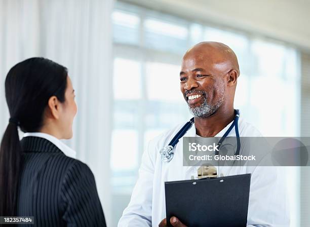 Foto de Masculino Médico Falando Com Seu Colega E Sorrindo e mais fotos de stock de Doutor - Doutor, Sexo Masculino, 40-44 anos
