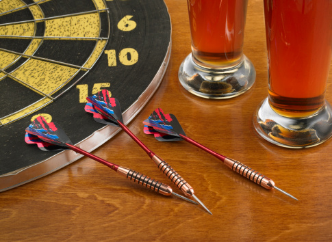 Three darts sitting on a bar with 2 glasses of beer. XXXL format.