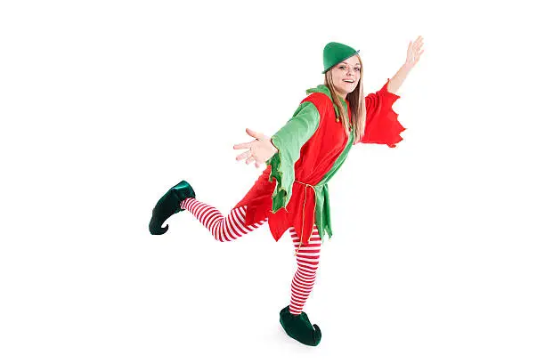 Full length photograph of cute Christmas elf in green and white costume posing as if sliding, skating, or dancing; copy space 