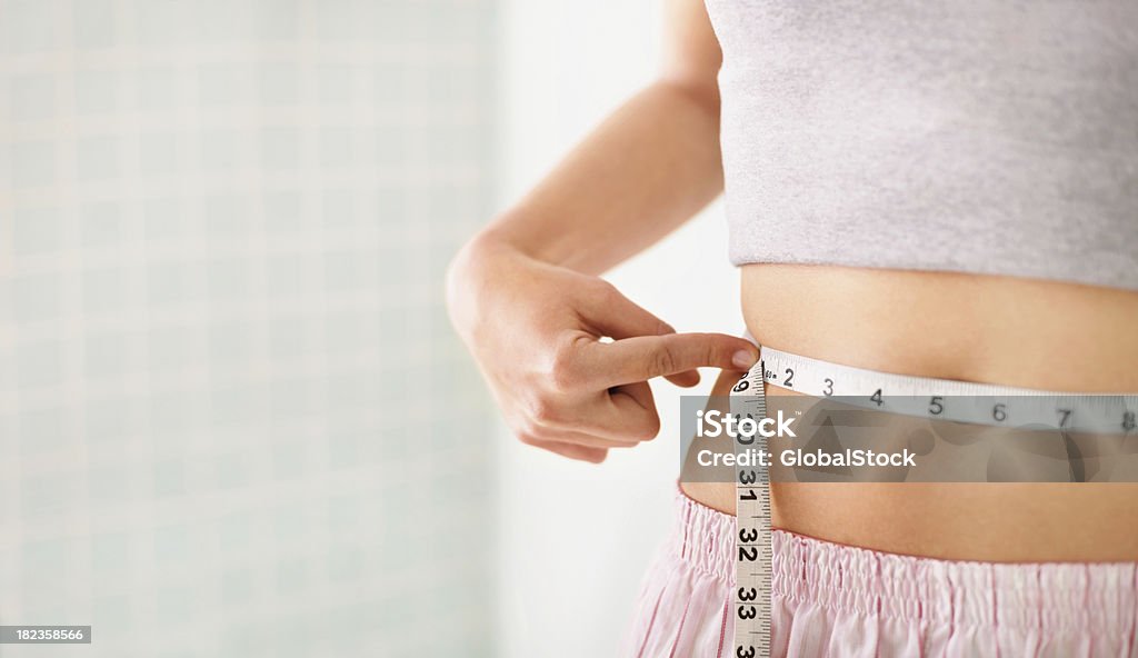 Femme mesurant sa taille sur blanc - Photo de Régime amaigrissant libre de droits