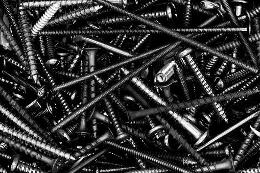 Black and white closeup if assorted screws, nuts, and bolts.