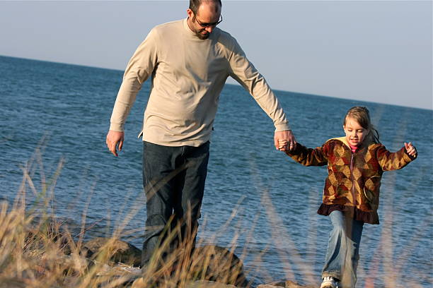 istock Father and Daughter Walking on Beach 182360536