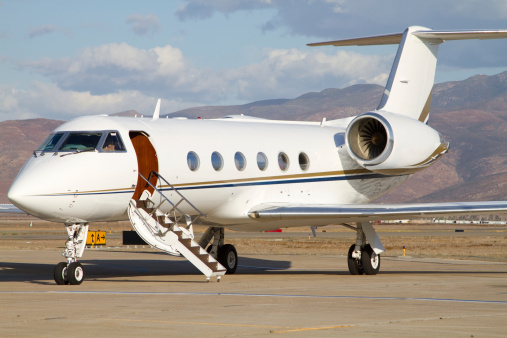 A large business jet waiting for passengers at a small airport.