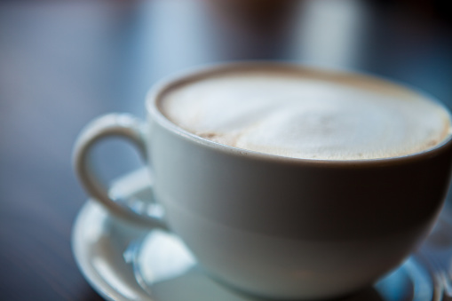 Detail shot of a foamy cup of cappuccino in a cafe.