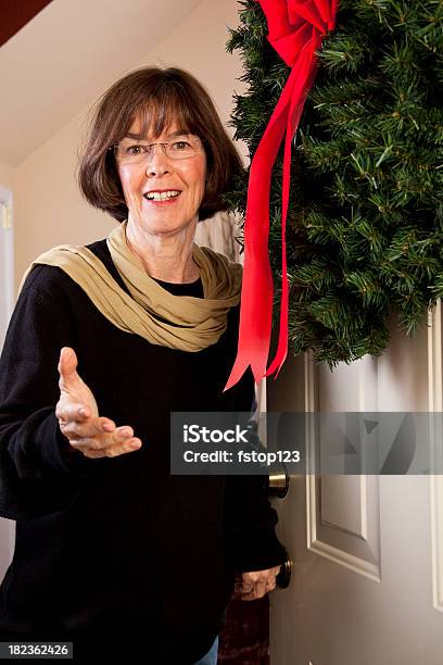 Senior Woman Opening Front Door Christmas Wreath Stock Photo - Download Image Now - Senior Adult, Wreath, Christmas
