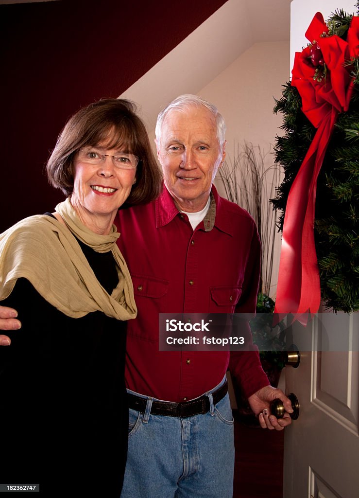 Casal de idosos abertura de porta da frente da coroa de Natal - Foto de stock de Abrindo royalty-free