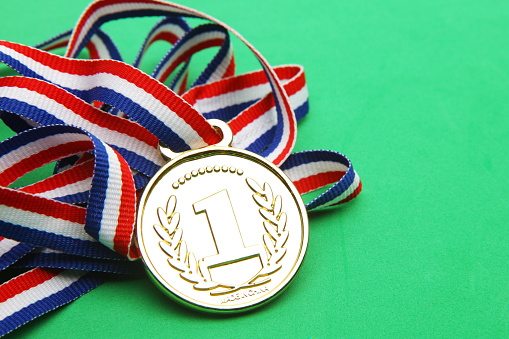 Winning medal. First place gold medal with red, white and blue ribbon. Lanyard with first place winning medal attached to it. Winning medal with a green background and a red, white and blue ribbon. Winning medal with a number one on the front.